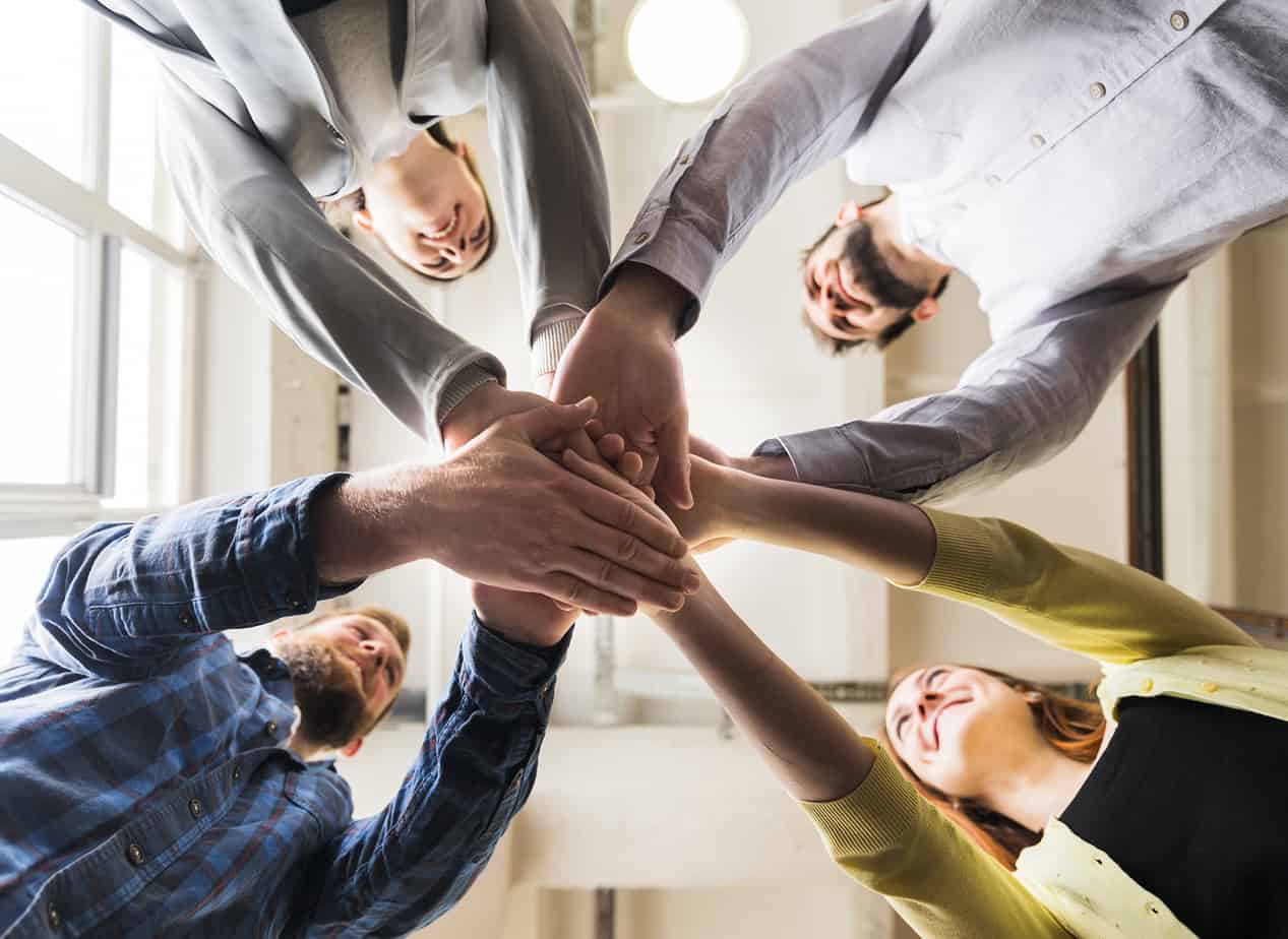 low-angle-view-of-businesspeople-stacking-hand-together-at-workplace low-angle-view-of-businesspeople-stacking-hand-together-at-workplace